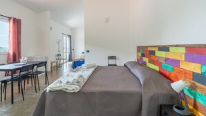 Une chambre à coucher avec un lit, un bureau, des chaises, une lampe et un mur aux couleurs vives.