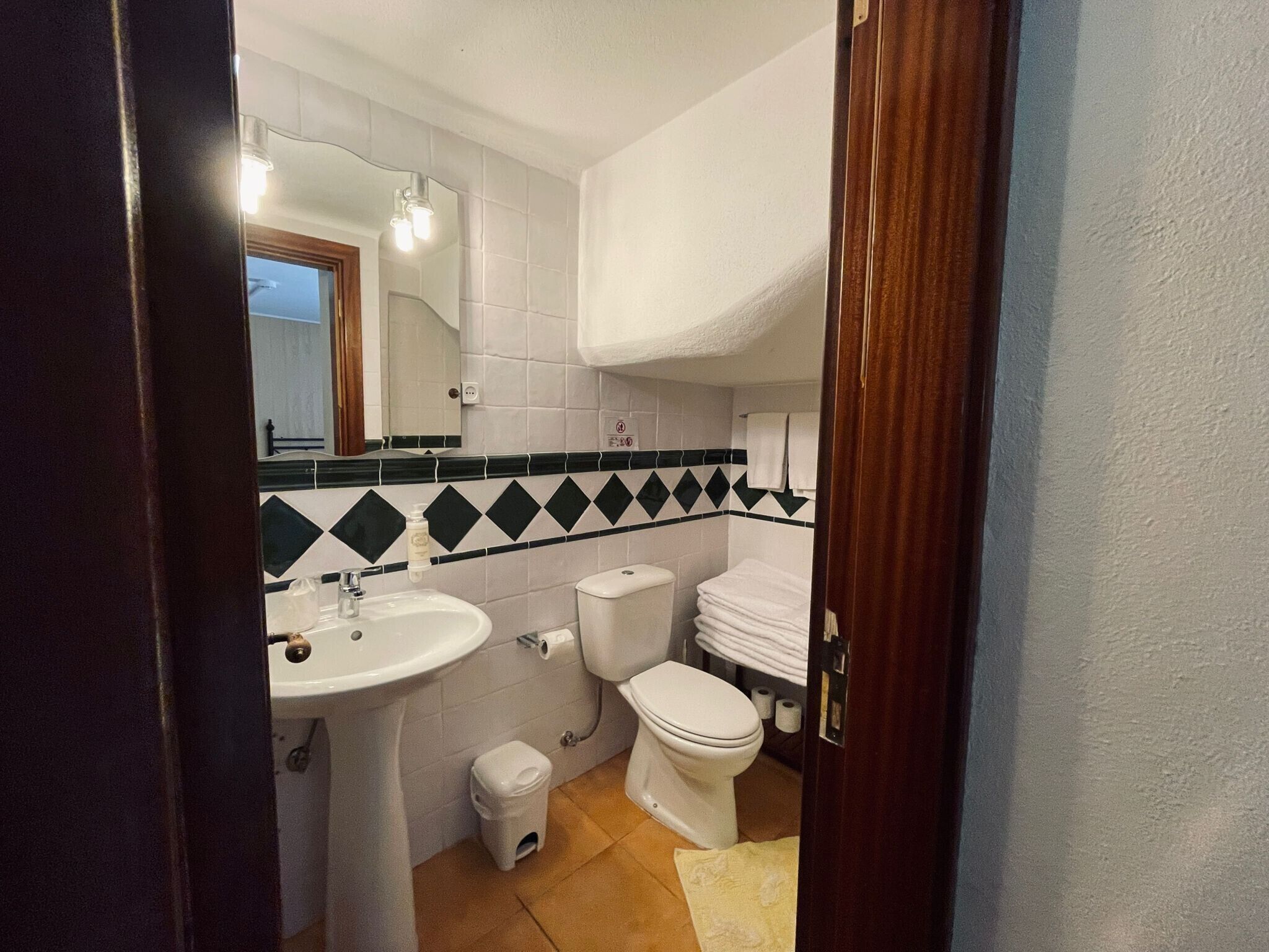 Un baño con lavamanos, inodoro y espejo.