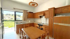 Une cuisine avec des meubles de rangement en bois, une cuisinière et une table à manger.