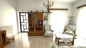 Ein Zimmer mit einem Holzkasten, zwei Polsterstühlen, einem Tisch und einer Heizung.