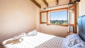 Ein Schlafzimmer mit Bett, einem Fenster und Blick sowie einer Holzbalkendecke.