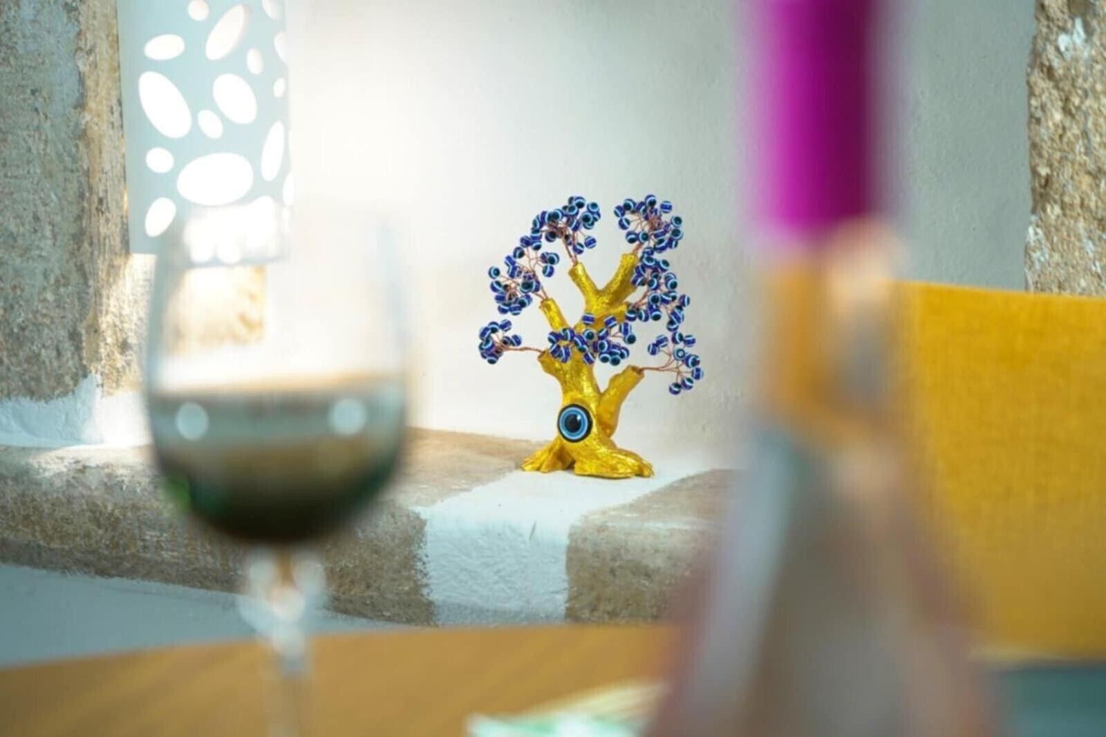 A table with a decorative golden tree sculpture, a candle, and a glass of wine.