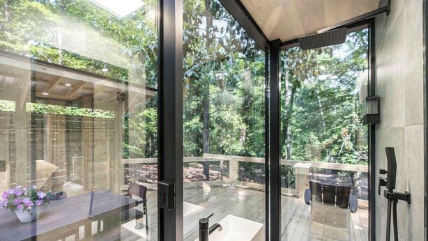 A modern kitchen with a large window, a built-in sink, and a wooden deck visible through the glass. - Mirror House Escape + Sauna/Cold Plunge (Macon)