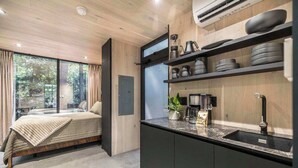 A modern kitchen with a built-in stove, a sink, and a window overlooking a garden. - Mirror House Escape + Sauna/Cold Plunge (Macon)