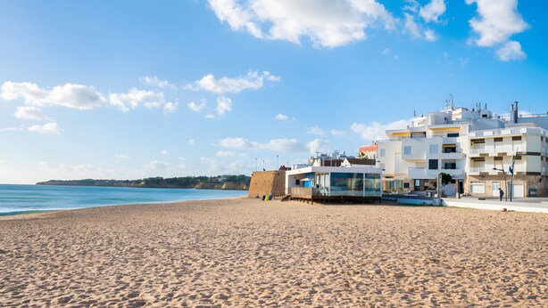 Een strand met gebouwen op de achtergrond.