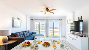 Een moderne hotelkamer met een zithoek, een bank, een televisie en een balkon met uitzicht.