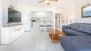 Een moderne woonkamer met een bank, een salontafel en een eethoek met een tafel en stoelen.