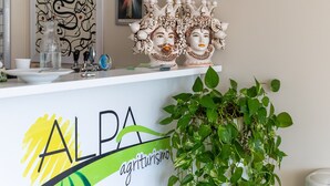 A reception desk with a logo, a vase, and a potted plant. - Apartment 'Sciroccu' with Outdoor Pool, Wi-Fi and Air Conditioning (Mazzarino)