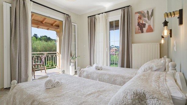 A hotel room with two beds, a balcony, and a view of greenery. - Apartment 'Villa Logas 2' with Mountain View, Wi-Fi and Air Conditioning (Peroulades)