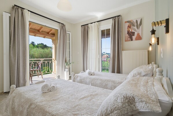 Ein Hotelzimmer mit zwei Betten, einem Balkon und Blick ins Grüne.