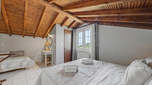 A bedroom with a wooden ceiling, a bed with white linens, a bedside table, and a window with curtains. - Apartment 'Villa Logas 2' with Mountain View, Wi-Fi and Air Conditioning (Peroulades)