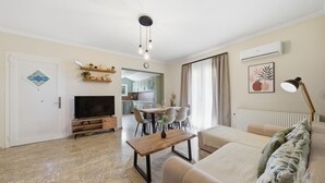 A living room with a TV, sofa, coffee table, and dining area with chairs. - Apartment 'Villa Logas 2' with Mountain View, Wi-Fi and Air Conditioning (Peroulades)
