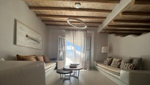 A modern living room with a wooden ceiling, a round table, and two sofas with patterned cushions. - Villa 11.7 – Luxus über dem Elia Beach, Mykonos (Elia)