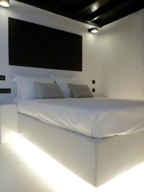 Une chambre à coucher moderne avec un grand lit, une literie blanche et une tête de lit sombre.