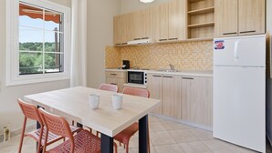 A modern kitchen with wooden cabinets, a white refrigerator, a microwave, and a dining table with chairs. - Studio Apartment '4' with Mountain View, Wi-Fi and Air Conditioning (Syvota)