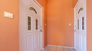 A hallway with two white doors, a light switch, and a tiled floor. - Studio Apartment '4' with Mountain View, Wi-Fi and Air Conditioning (Syvota)