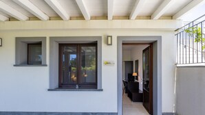 A building entrance with a covered porch, a door leading inside, and a small window with a lamp. - Lustru Room with Mountain View, Wi-Fi, and Air Conditioning (Mazzarino)