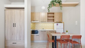 Una cocina con armarios de madera, microondas, refrigerador y una mesa de comedor con sillas.
