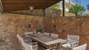 Un patio exterior con pared de piedra, una mesa con sillas y un colgante de luz.