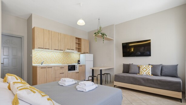 Ein modernes Hotelzimmer mit Bett, einer Couch, einer Küchenzeile und einem Fernseher.