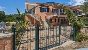 Ein zweigeschossiges Haus mit einer Steintreppe, einem Metallgitter und einem Garten.