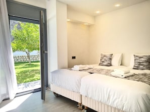 Une chambre à coucher avec un lit, des oreillers et une vue sur un arbre et un mur de pierres.