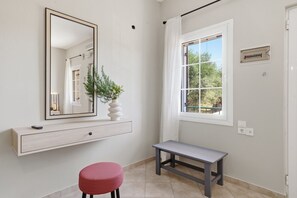 Ein Badezimmer mit Spiegel, Sitzbank, Pflanze und Fenster.