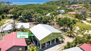 Un bâtiment écologique, baptisé «Little Roatan Retreat», avec un toit rouge, entouré d’une végétation luxuriante et offrant une vue sur l’océan.