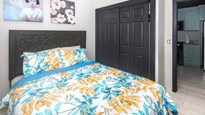 Une chambre à coucher avec un lit, une tête de lit sombre, une armoire et un tableau accroché au mur.