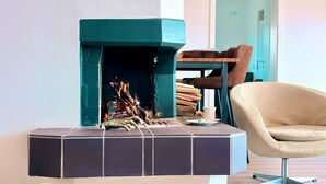 Una sala de estar moderna con chimenea, una mesa de centro redonda, un sillón color beige y una silla de madera.