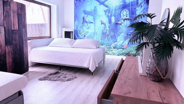 A bedroom with a bed, a wooden bench, a potted plant, and a large wall mural.