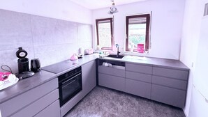 Una cocina compacta con horno empotrado, un lavamanos y una ventana con vistas.