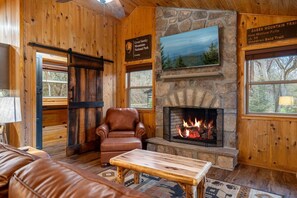Ein gemütliches Blockhaus-Interieur mit Kamin aus Stein, Ledermöbeln und einem Schild, das auf den Great Smoky Mountains National Park hinweist.