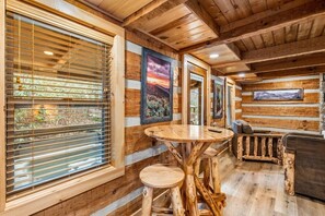 A log cabin interior with wooden walls, a round wooden table, and a sofa. - Waterfront King Cabin A | Hot Tub & Fire Pit (Gatlinburg)