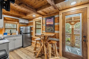 Ein Blockhaus-Interieur mit Küche, Essbereich und einem großen Fenster mit Aussicht.