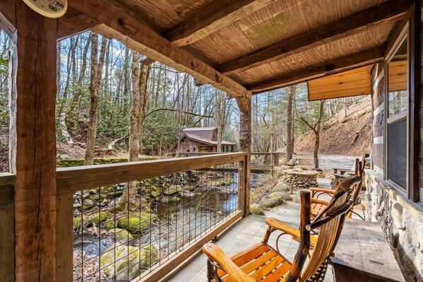 Eine Holzterrasse mit Blick auf einen Wald und einen Bach.