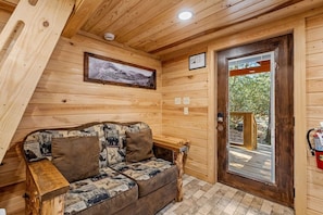 Ein Holzinterieur mit einer Couch, einem gerahmten Bild, einer Tür und einem kleinen Fenster.