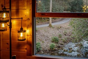 A wooden interior with hanging lantern-style lights and a window view of a forested area with a path. - Walking distance to best Smoky Mountain Hiking (Cosby)
