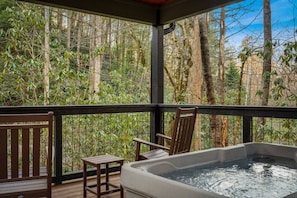 Ein Whirlpool auf einer Holzterrasse mit Blick auf einen Wald.