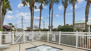 A pool area with a white fence, a metal handrail, and palm trees in the background. - Grand Caribbean East 112- Crystal Blu (Destin)