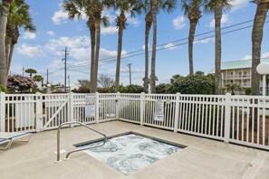 A pool area with a white fence, a metal handrail, and palm trees in the background. - Grand Caribbean East 112- Crystal Blu (Destin)
