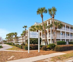 A multi-story hotel with a sign reading 'Grand Caribbean East.' - Grand Caribbean East 112- Crystal Blu (Destin)