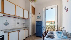 Una cucina compatta con mobili bianchi, un frigorifero blu e un'area pranzo con un tavolo apparecchiato per quattro persone.