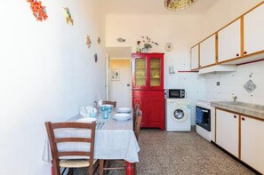 Een compacte keuken met een wasmachine, magnetron en een rode kast.