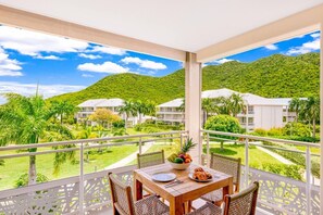 Ein Balkon mit Holztisch, Stühlen und einer Obstschale.