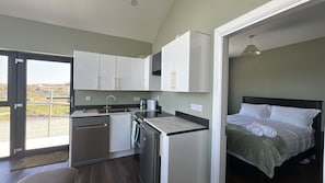 A modern kitchen with white cabinets and a built-in dishwasher. - Calla Retreat (Roundstone)