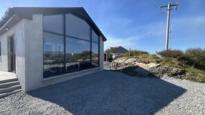 Ein modernes Gebäude mit großen Fenstern, einer Schotterauffahrt und einem Strommast im Hintergrund.