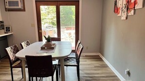 Zona pranzo con tavolo rotondo, sedie e vista attraverso una porta in vetro.