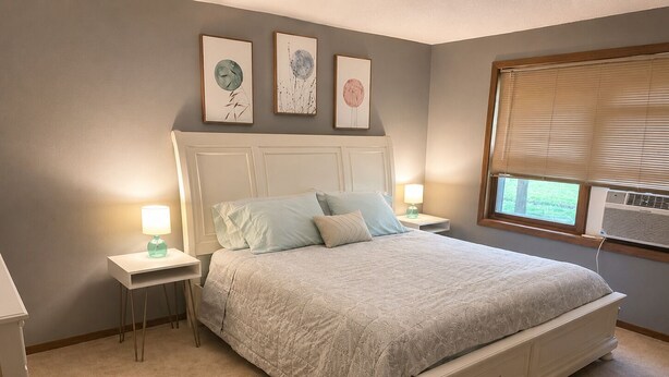 Una camera da letto con un letto, comodini, lampade e decorazioni alle pareti.