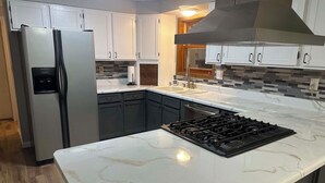 Una cucina moderna con frigorifero in acciaio inossidabile, piano cottura a gas e un'elegante superficie in marmo.